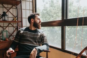 Person sitting indoors looking out a window representing PTSD treatment in Lincoln Nebraska and trauma related nervous system healing.