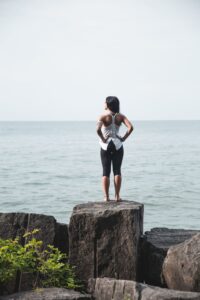 Woman standing on rocks overlooking the ocean representing hope and chronic pain treatment in Lincoln Nebraska.