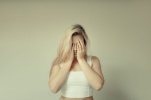 Woman covering her face with her hands representing burnout and mental health and emotional exhaustion.